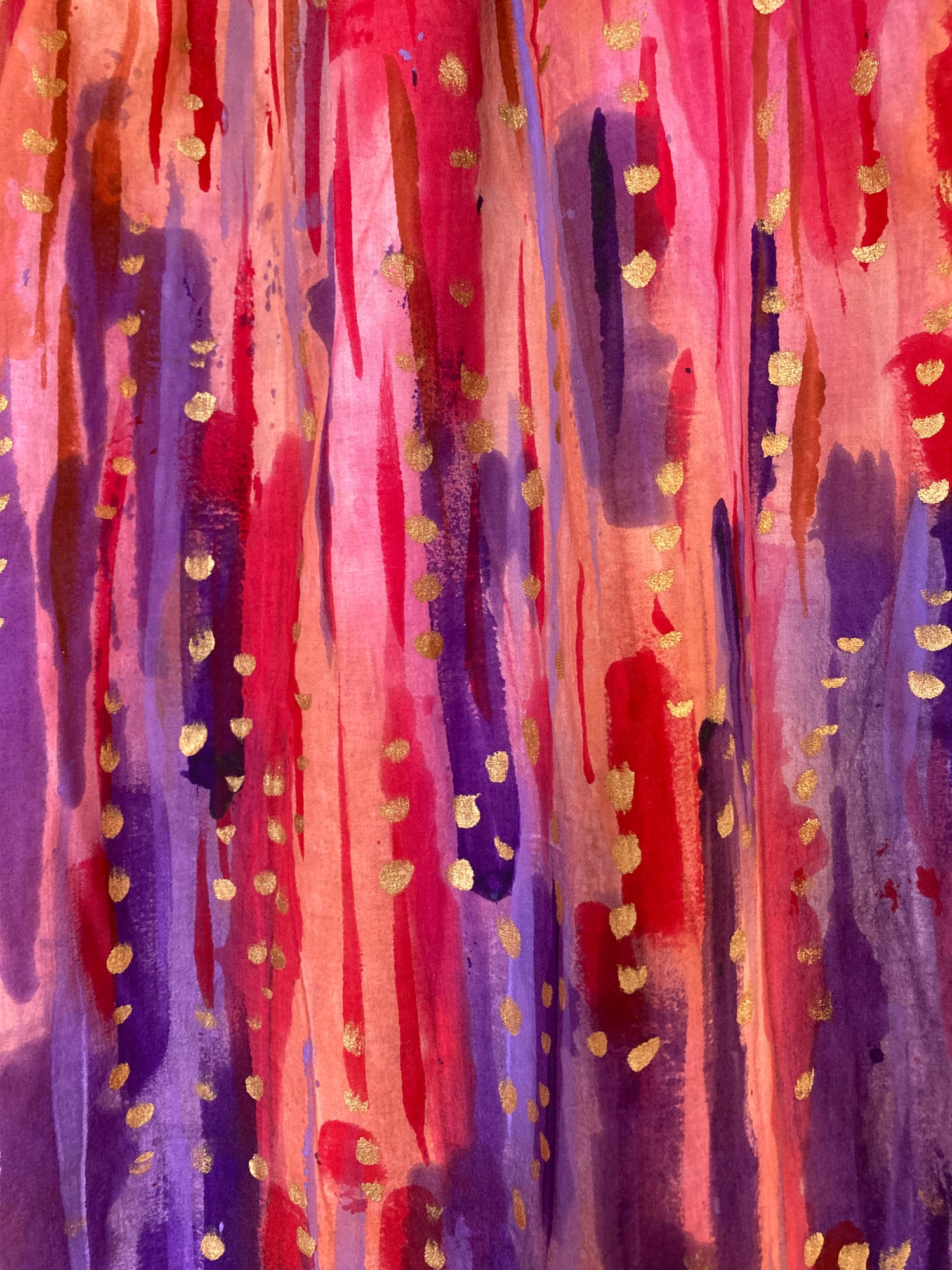 Handpainted fabric. Strokes of dadk/mid purple are concentrated towards rhe bottom, with salmon orange and red strokes concentrated towards the top. Gold dots accent the paintstrokes. 