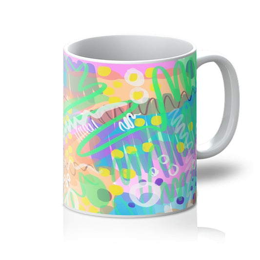 White mug with art print. Abstract line drawing. It uses green/yellow/purple/pink/blue/yellow. The colours are fresh and bright. there are circles, squiggles and dots. Handle is on the right. 