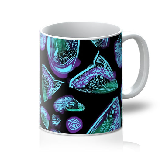 A white mug printed with art. An abstract drawing of sea shells arranged in a circle. The background is black and the design is sea shells rendered with dark green/purple wash and light blue line markings. Handle is on the right. 