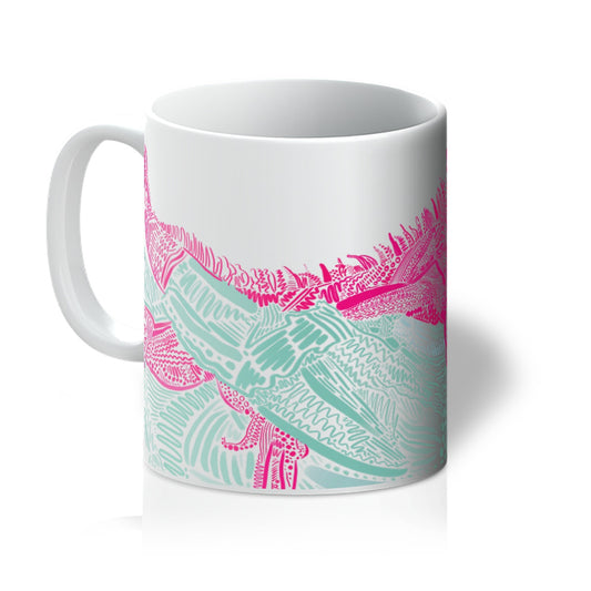 White mug with art print. design is an Iguana laying on top of a branch. They are both rendered in lines, squiggles and circles. The Iguana is mid pink and the branch is jade green. You can see the branch and the feet of the Iguana, indicating that we are looking at the middle of its body. The mug handle is to the left. 