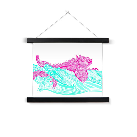 A black wooden poster hanger. The print background is white and the design is an Iguana laying on top of a branch. They are both rendered in lines, squiggles and circles. The Iguana is hot pink and the branch is seafoam green.