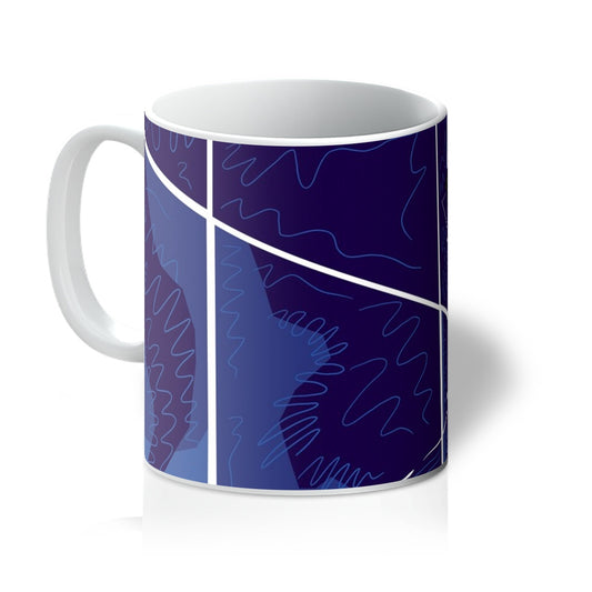 White mug with art print. Blue squares, with white lines that indicate they are tiles, and squiggle accents. Handle is on the left. 